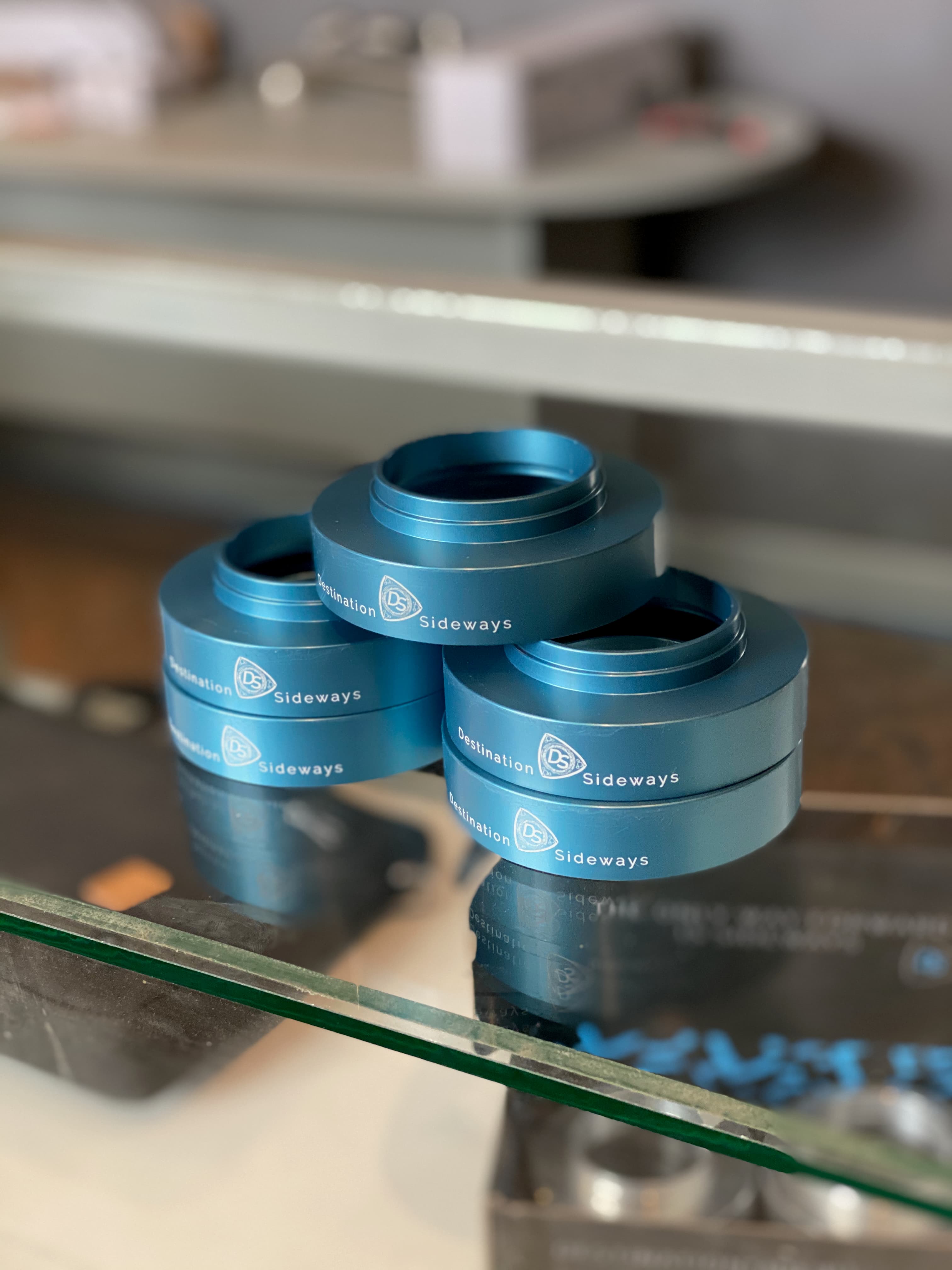 Blue V1 60 mm Radial Adapters, engraved Destination Sideways, stacked on a glass counter.