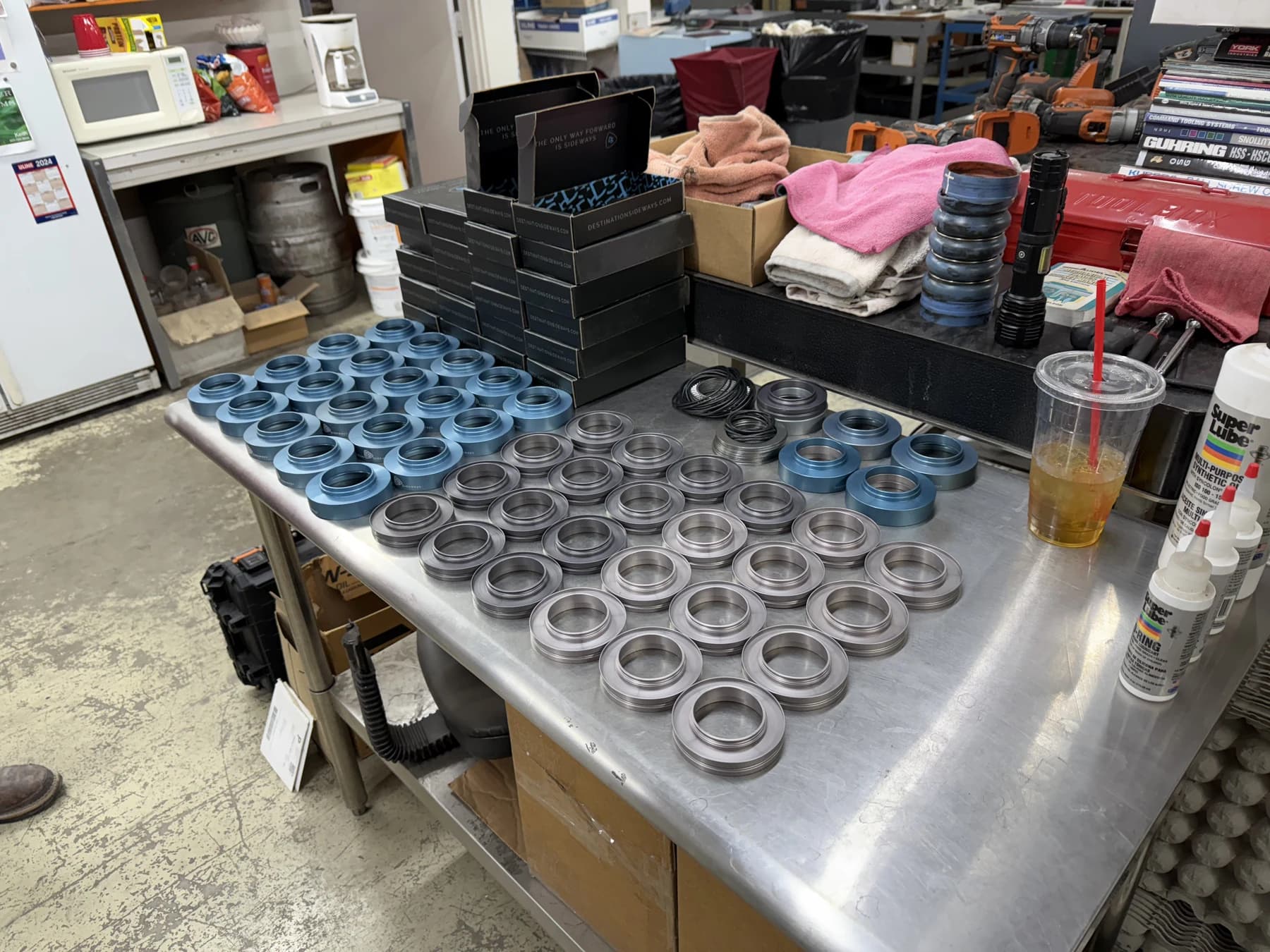 Rows of blue and silver machined housings laid out separately on a workbench with seals nearby.