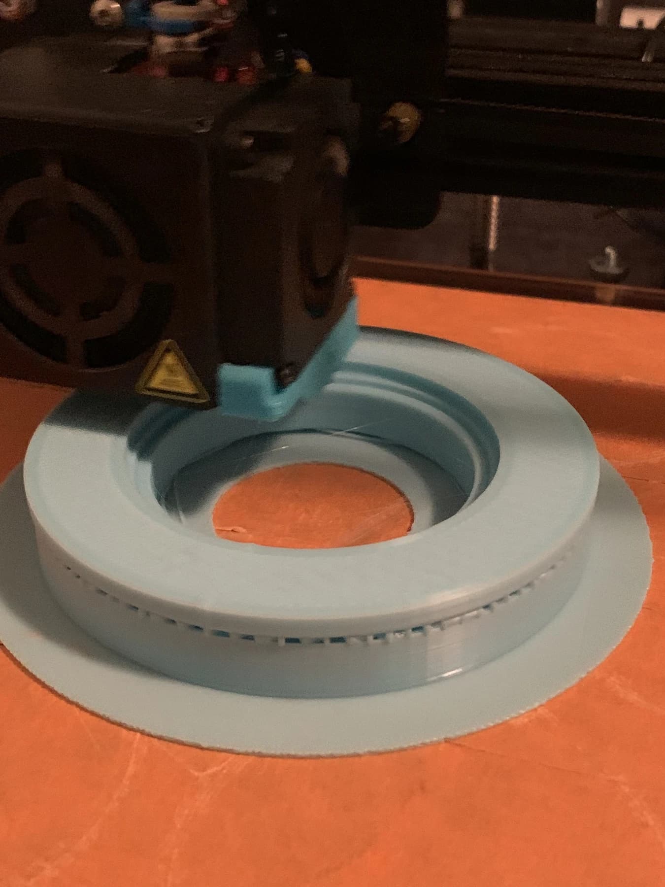 A pale blue housing on the bed of a desktop 3D printer.