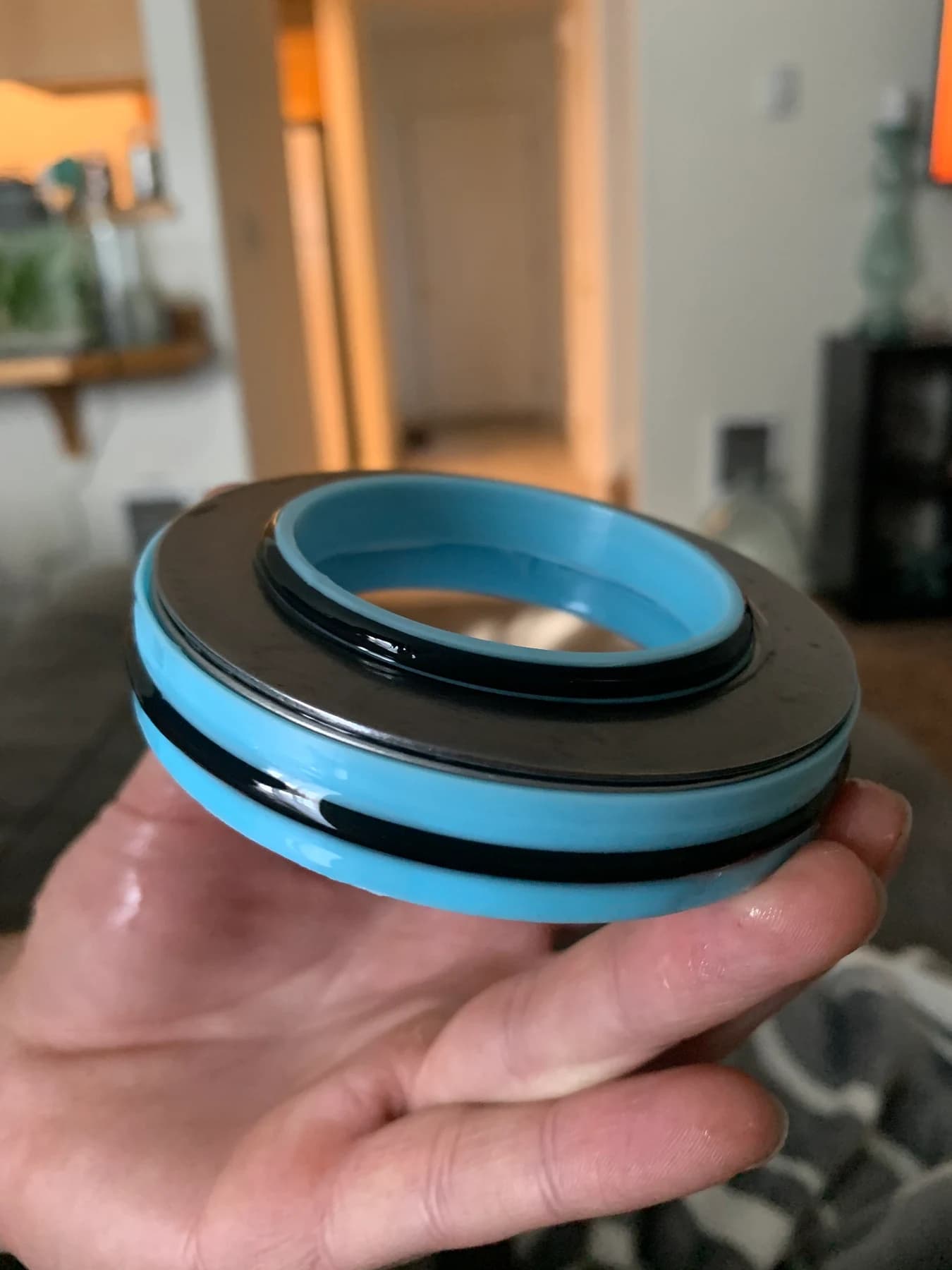 Blue housing held in a hand with a black seal around its upper edge.